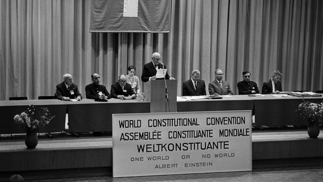 In Photo (from left): Oscar Jedzini, President of the German World Federation, Ahmed E. H. Jaffer (Pakistan), Pastor Martin Niemöller, at the lectern Dr. Max Habicht, Chairman of the Organisation Committee, Governor Henri Huber, Kurt Borter, Mayor of Interlaken, Ambassador R. K. Nehru (India), Philip Isely, Secretary General WCPA (USA)